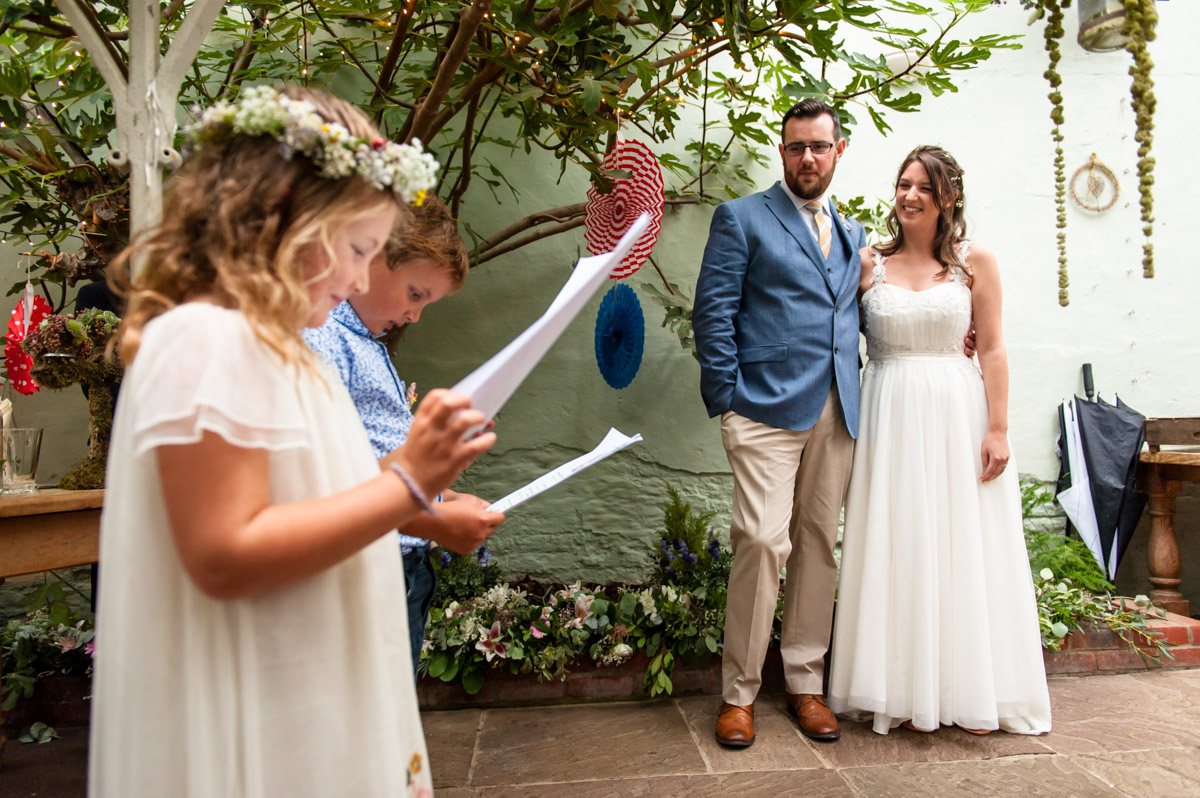 small children doing wedding readings at rachel and daniels wedding at the secret garden in Kent