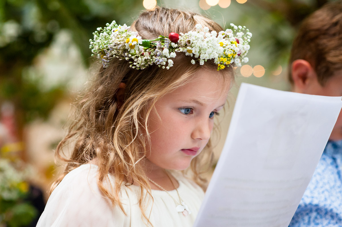 flower girl does wedding reading at rachel and daniels wedding ceremony in glass house at the secret garden in kent