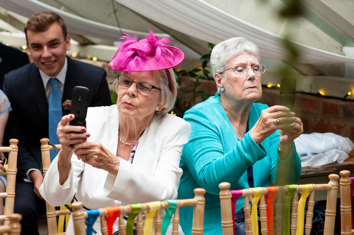 guests at rachel and daniels wedding take photos with their phones