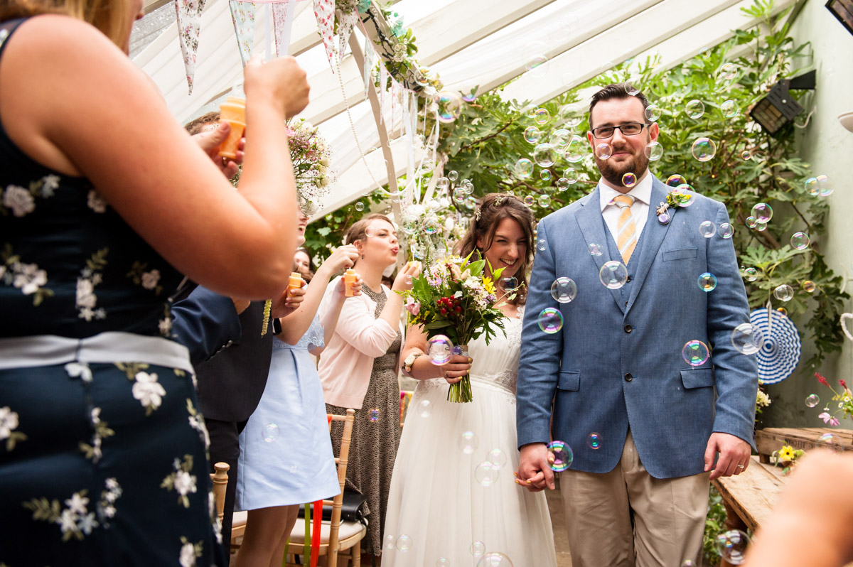 Bubbles, wedding procession, glass house ceremony in the secret garden kent