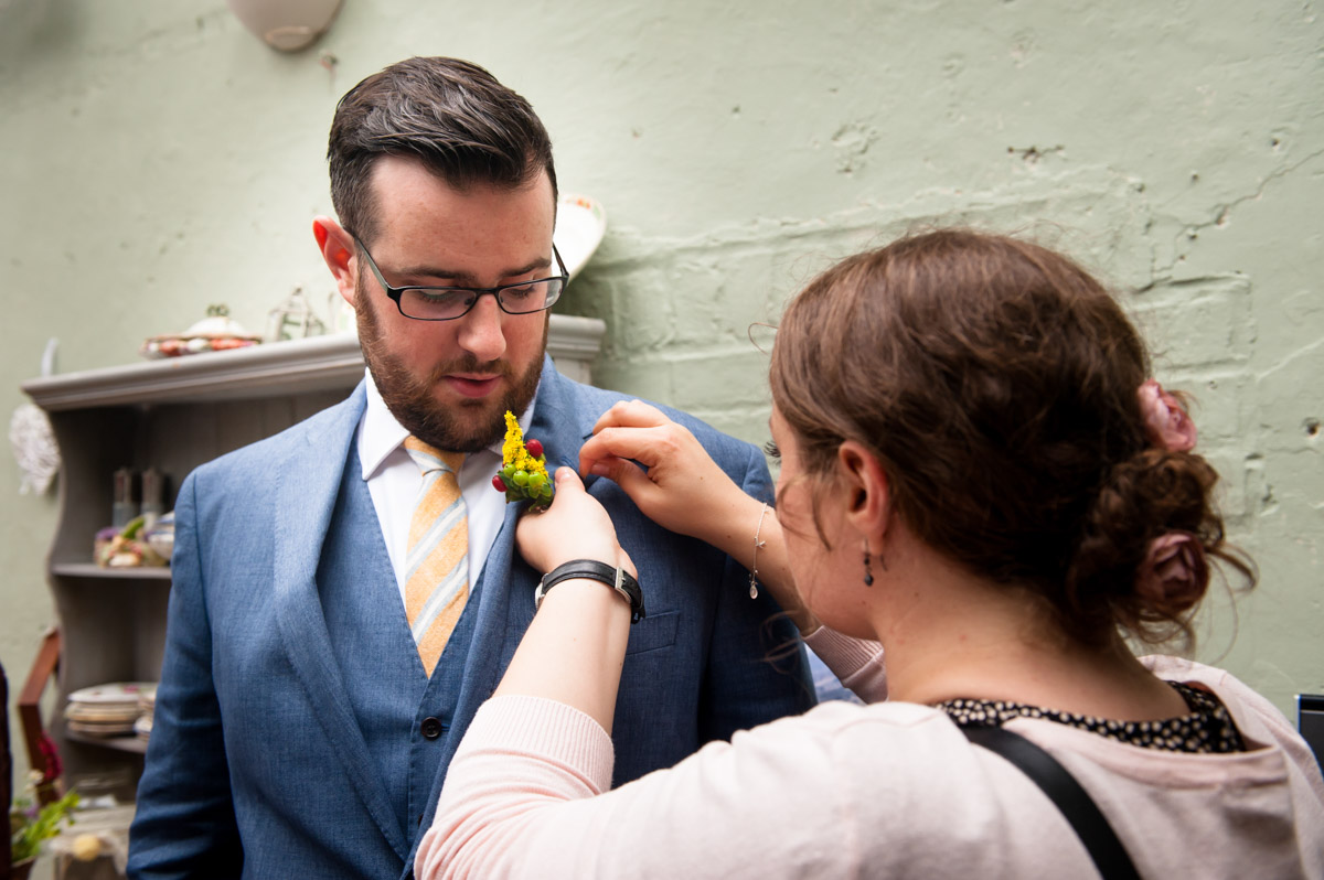 daniel is photographed being helped with button hole at his Secret garden wedding in Kent