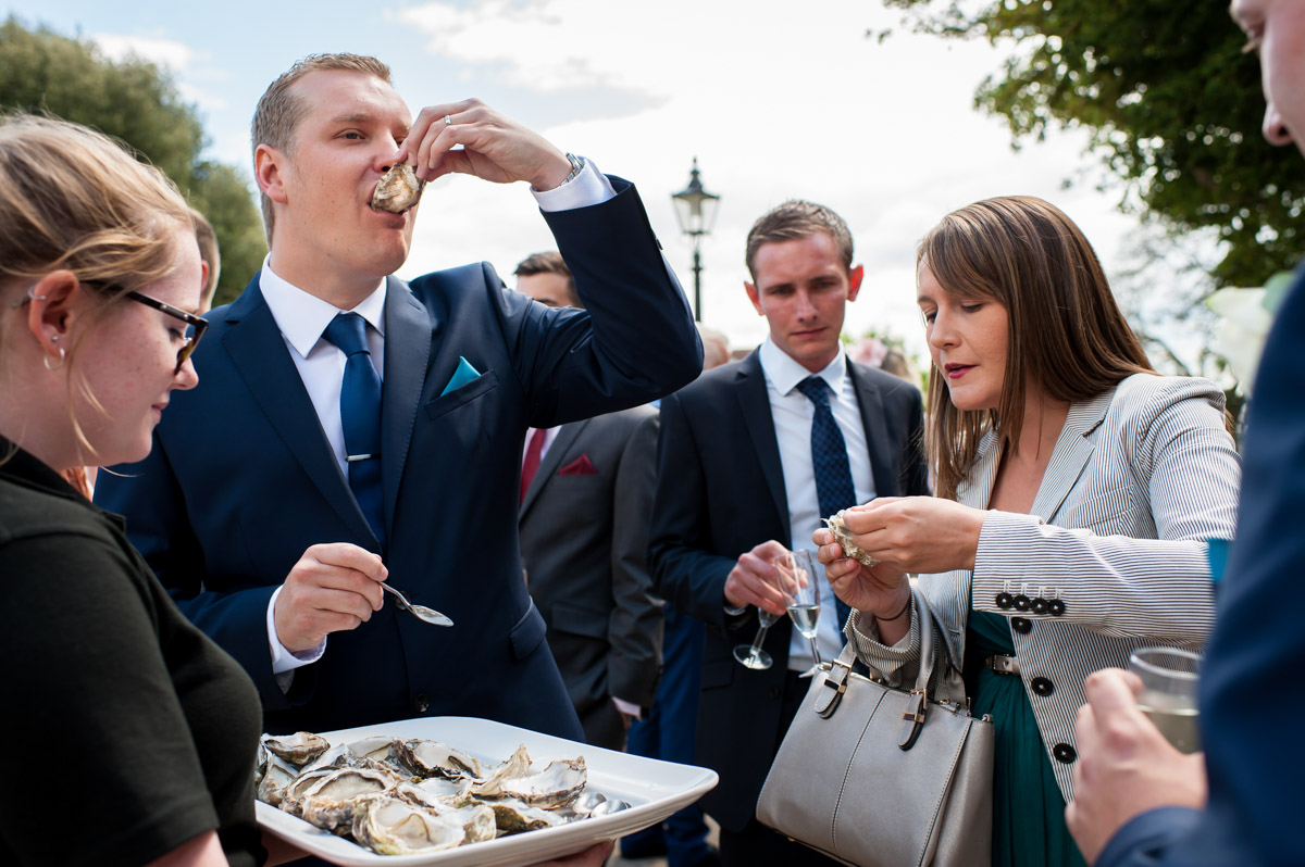 Photograph of groom eating oysters at his wedding reception at Whitstable castle in Kent