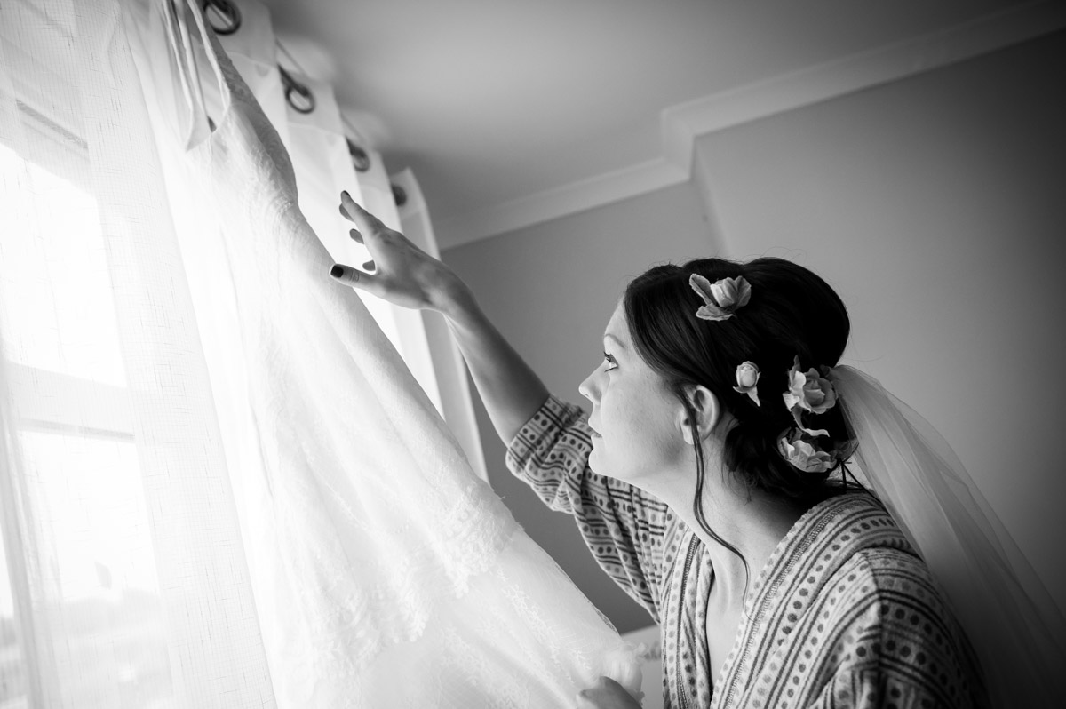 back and white photo of gaby reaching for her wedding dress