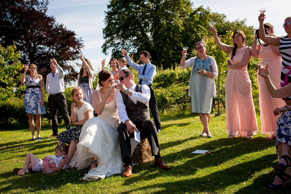 mark and gaby and wedding guests toast each other in garden of reception venue