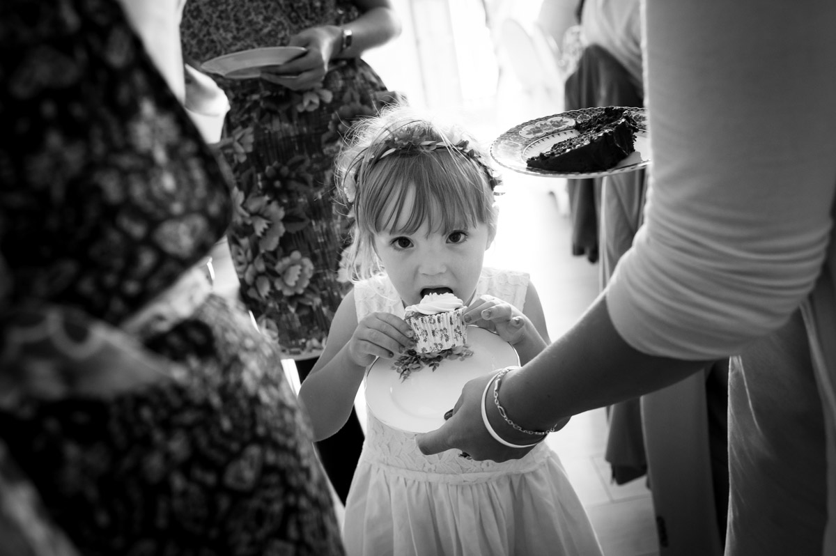 black and white photo of little girl eating cake at gaby and marks wedding reception