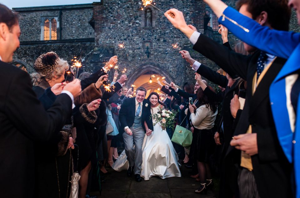 Marcus and Frances are photographed running under lit sparklers after their Kent wedding ceremony