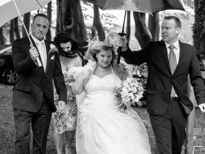 Stevie arrives at her wedding in the rain at The Crown in Wye near Canterbury in Kent