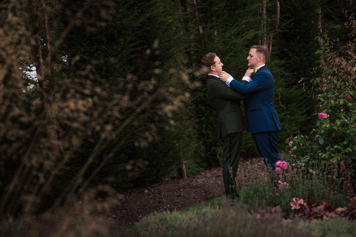 David and Simon fix their bow ties during their couple portrait session on their wedding day at port Lympne Mansions in Kent