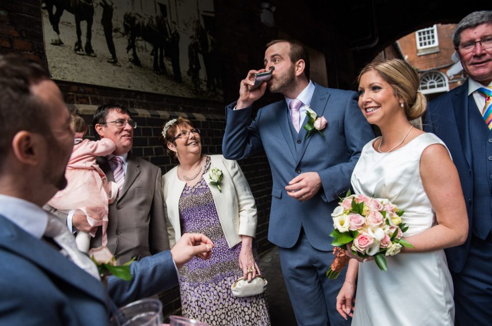 Mike has a drink from the hip flask during the wedding group photos at The Shepherd Neame Brewery in Faversham, Kent