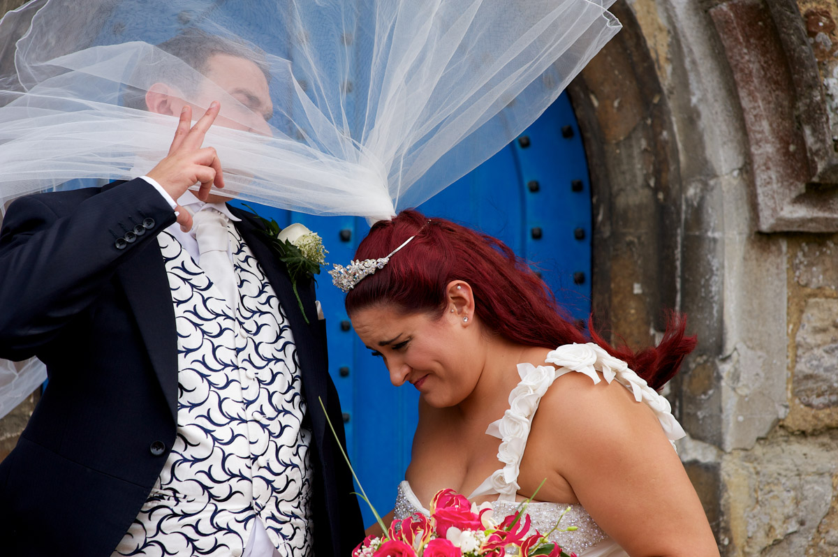Charlotte and Scott try to hang onto the wedding veil after their Kent wedding church ceremony