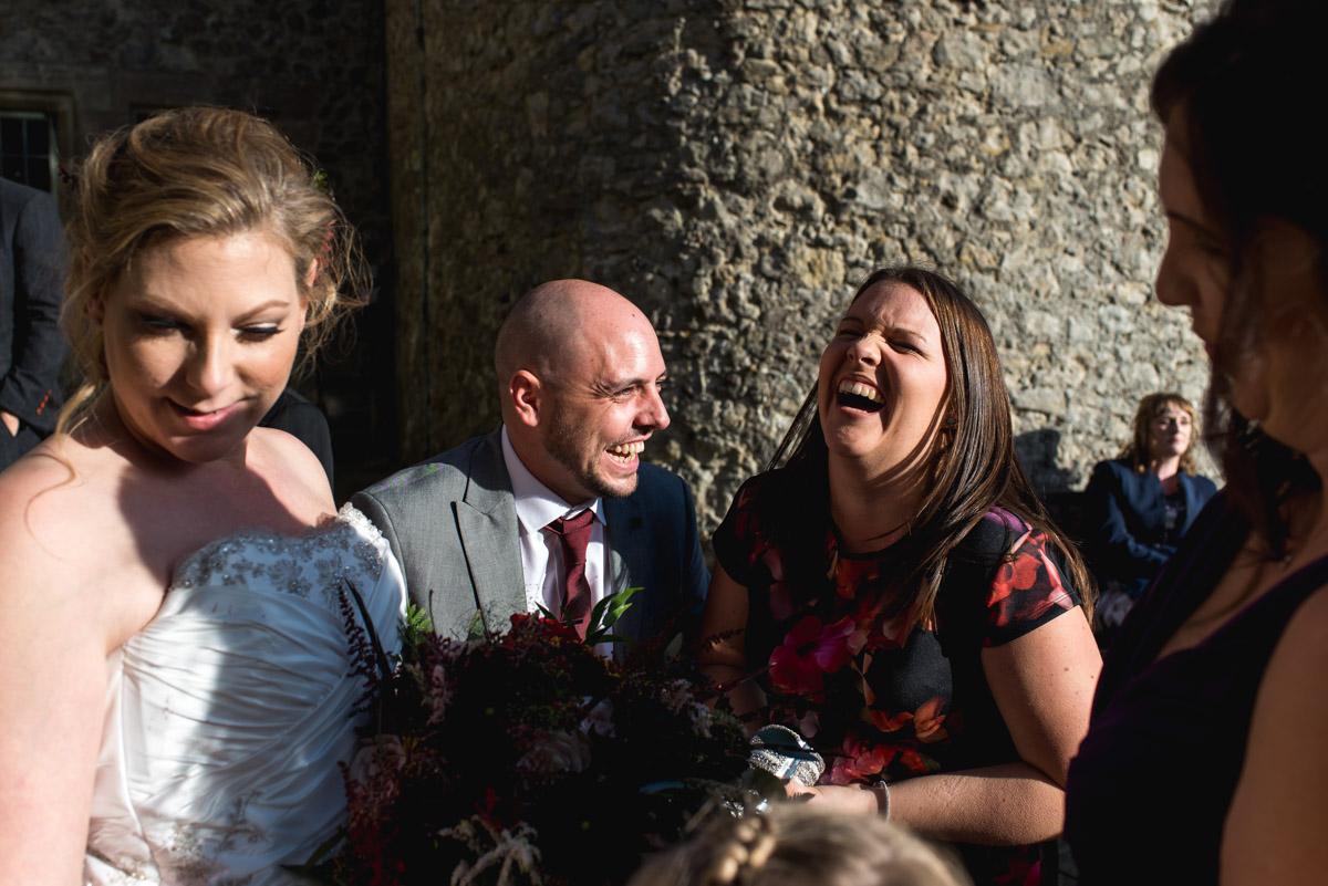 Photograph of guests enjoying a laugh outside in the grounds at Lympne Castle on Lianne and Johns wedding day