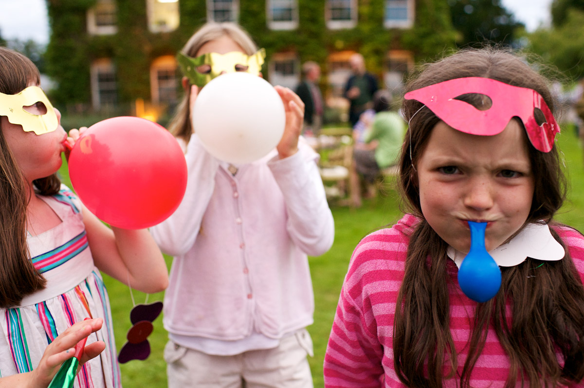Children play with balloons at David and Juliettes wedding celebration in Wye, Kent