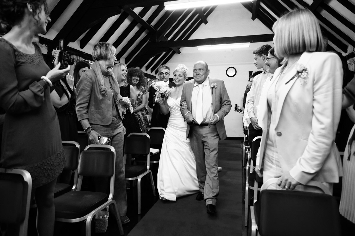 Emilys' dad walks her down the aisle at Chilham Village Hall in Kent on her wedding day