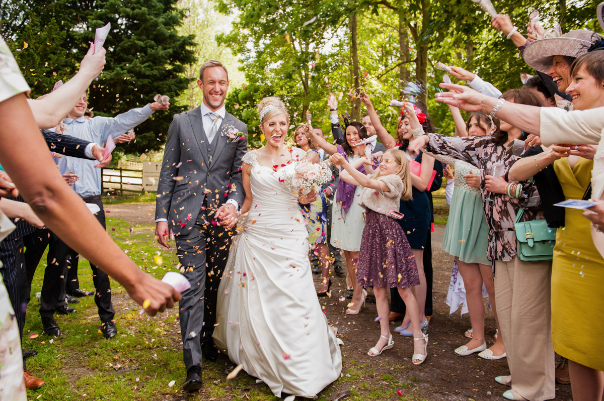 Rob and Emily are photographed having confetti thrown on their wedding in Kent