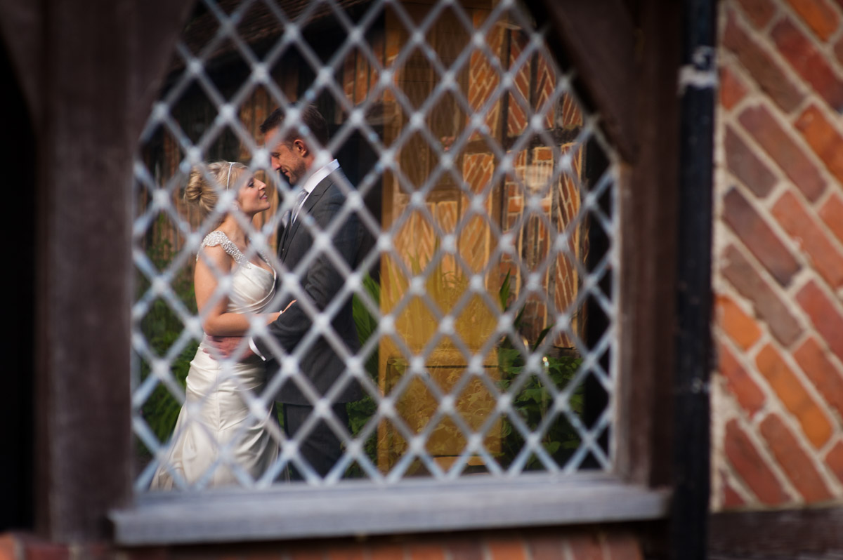 Emily and Rob are photographed reflected in Chilham, Village Hall window