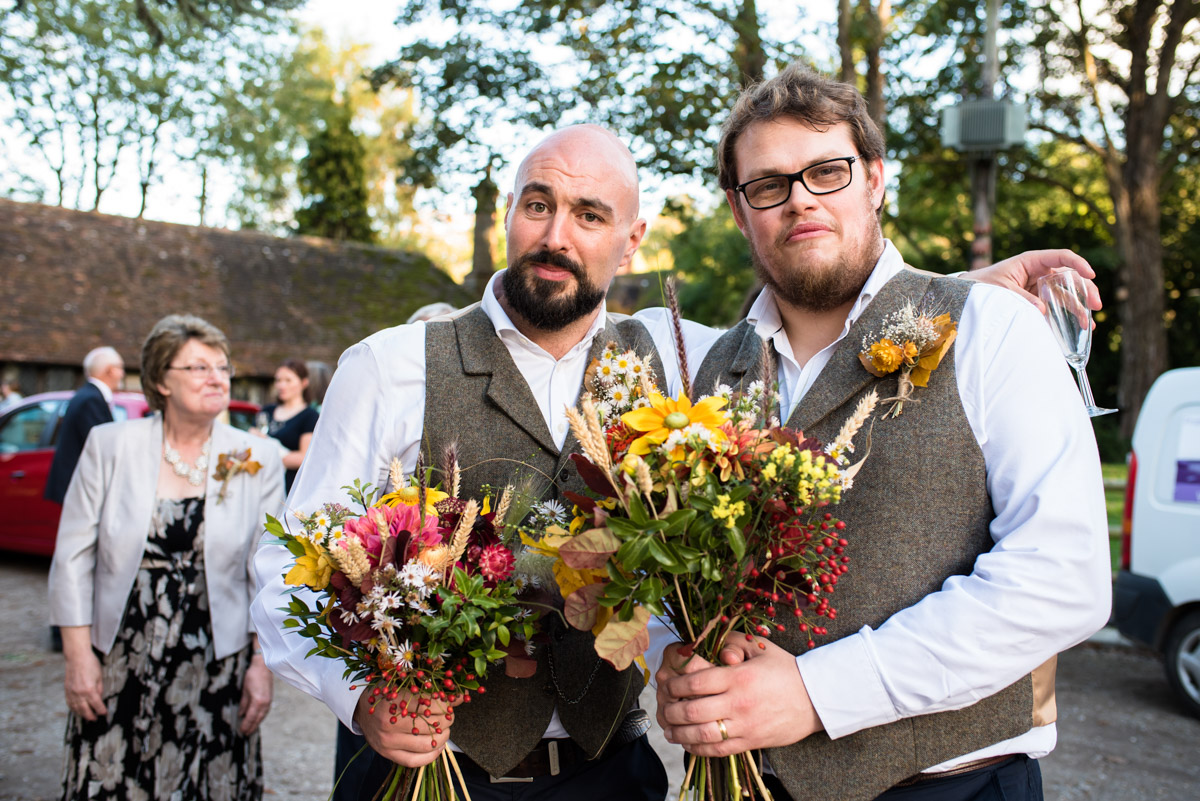 Groomsmen are photographed holding wedding flowers at Chilham Village Hall in kent