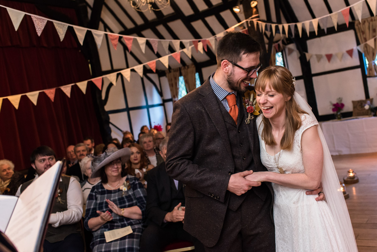 Laura and Paul are photographed sharing a joke after taking their wedding vows in kent venue Chilham Village Hall