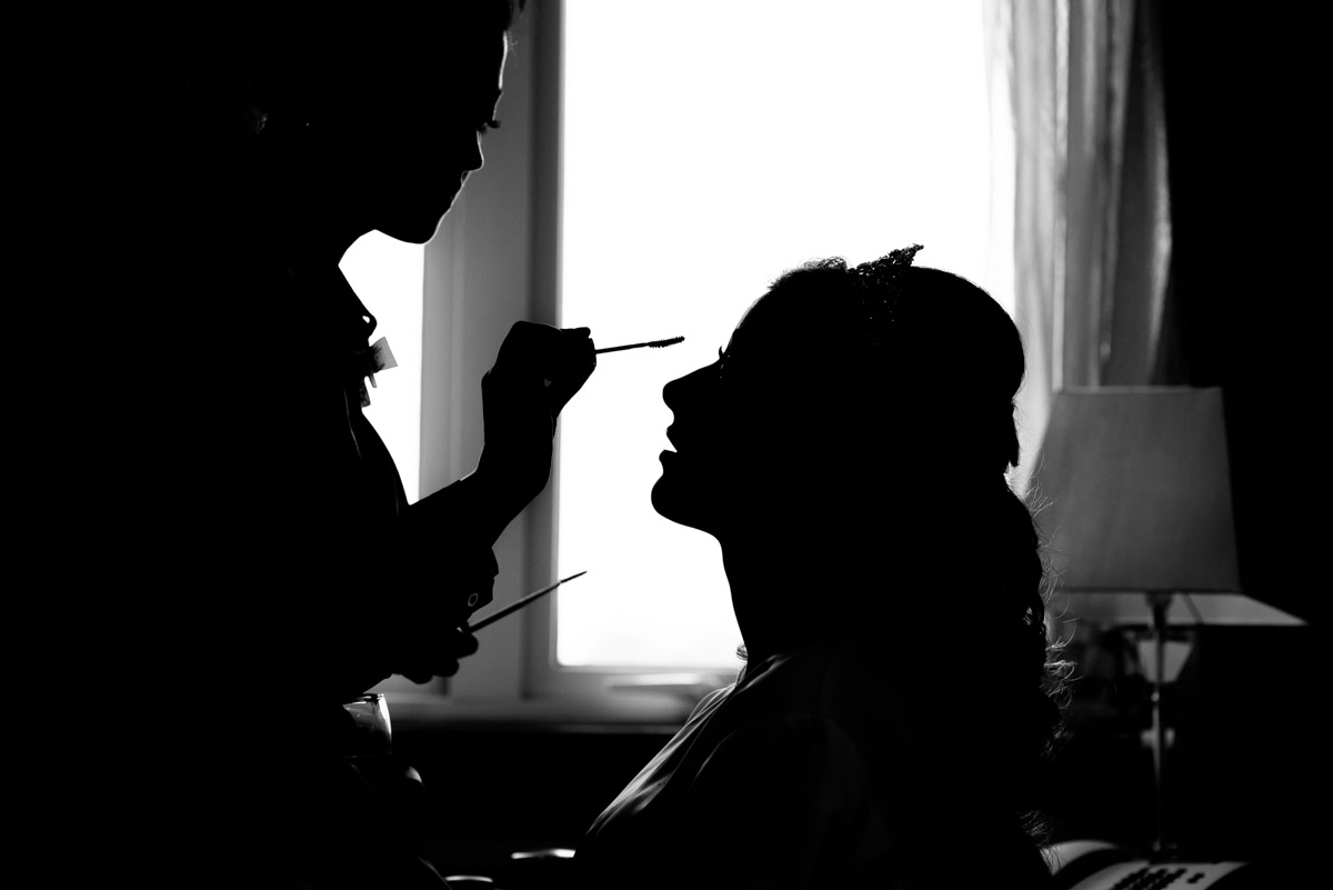 Black and white wedding photograph of Jade having her make up applied