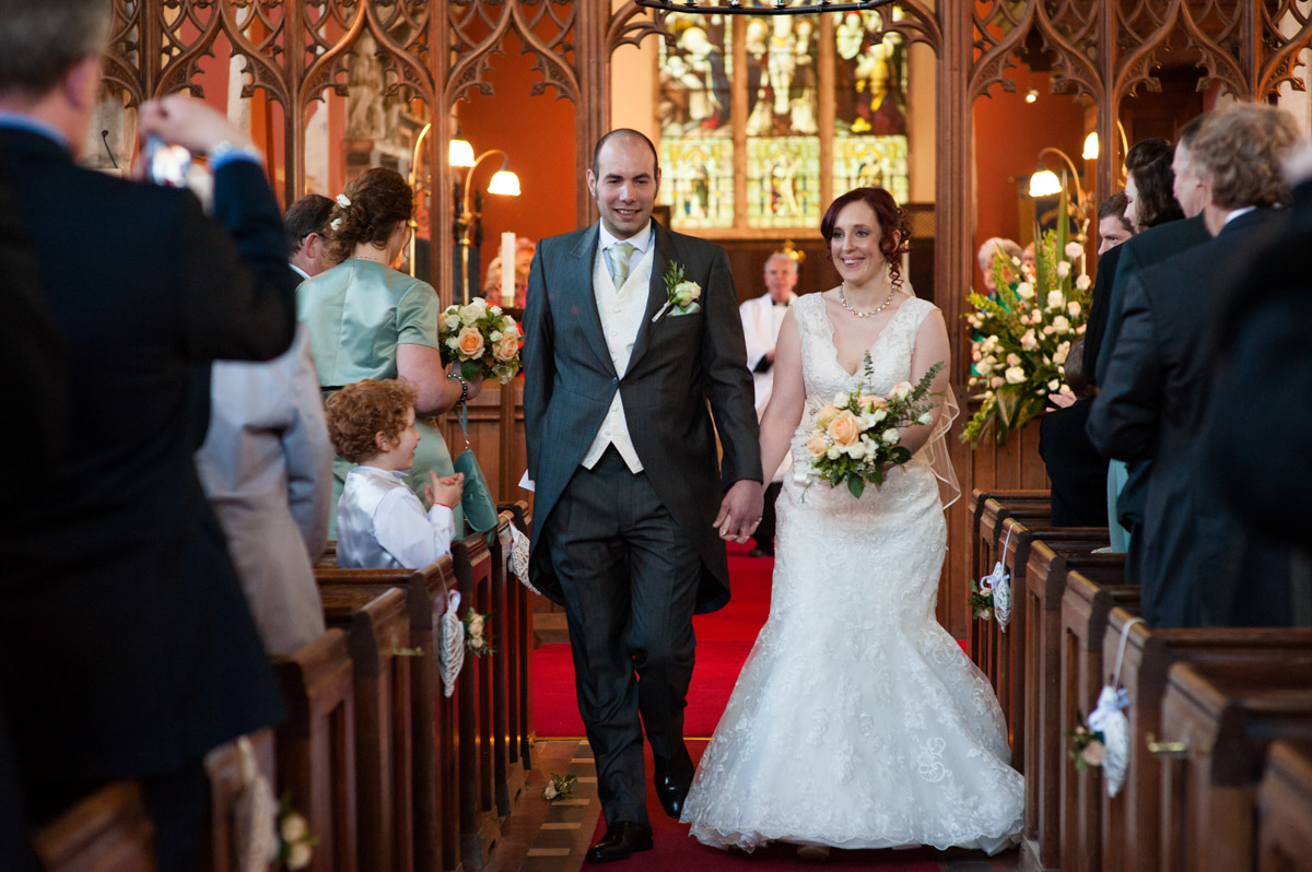 Photograph of charlotte and Chris exiting the church after their wedding ceremony
