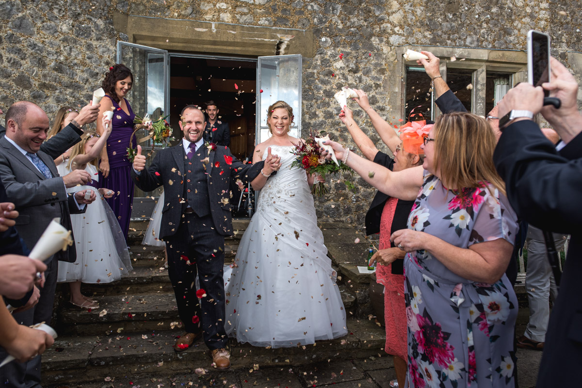 Photograph of Lianne and John and guests throwing confetti at their Kent wedding