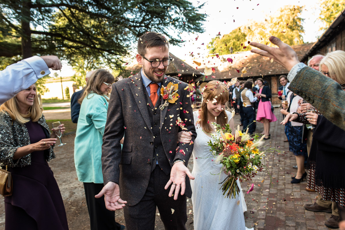 Photograph of Laura and paul during confetti throw at their Chilham Village hall wedding in Kent