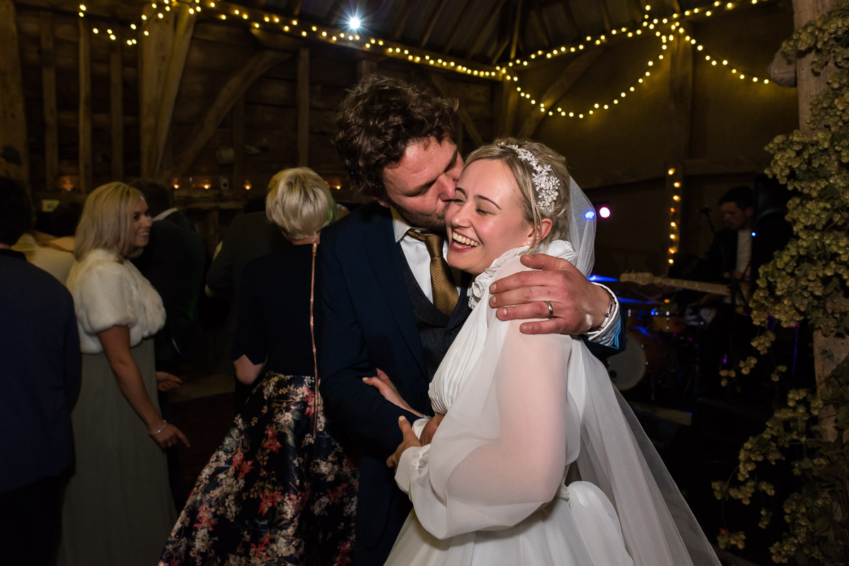 Steven plants a kiss on Janes cheek during their wedding reception after their Chilham church wedding in Kent