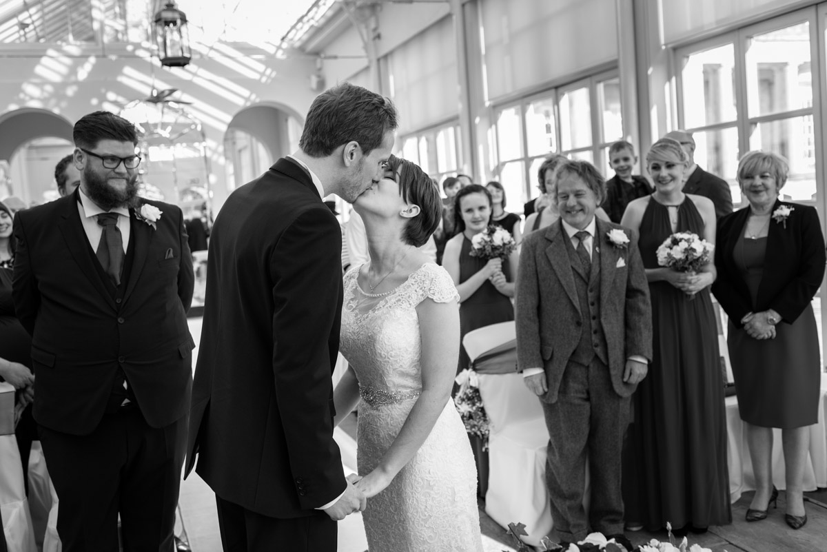 Black and white photograph of Joe and Bennets first kiss at Buxted park Hotel wedding