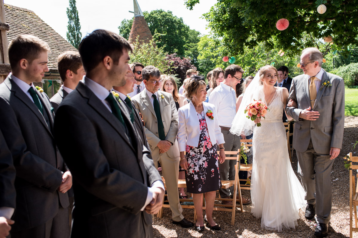 Bride is walked up the aisle by father for her wedding ceremony at Ratsbury Barn in Kent