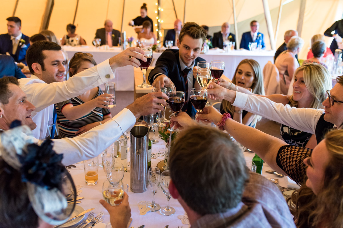 Tipi wedding photography in kent. Guests toast the bride and groom