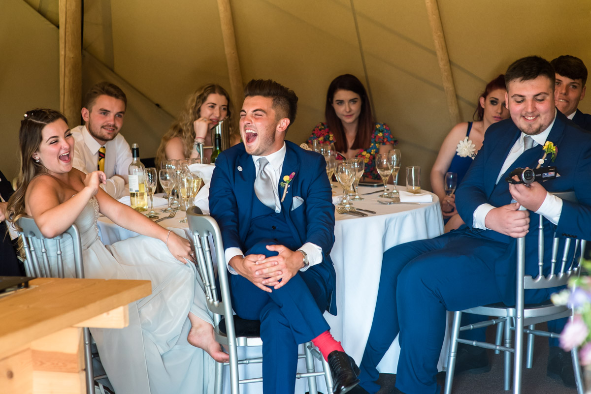 Family of the bride and groom photographed laughing at wedding speeches