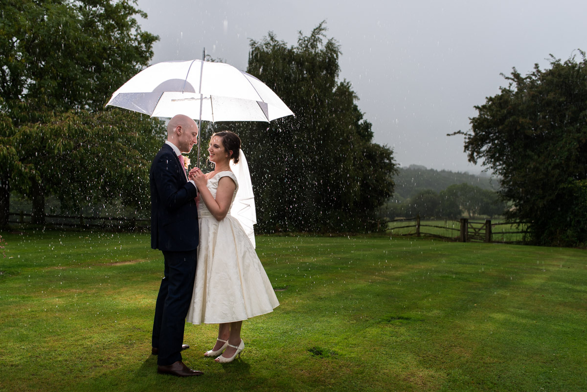 Photograph of Emily and Tom in the rain on their wedding day