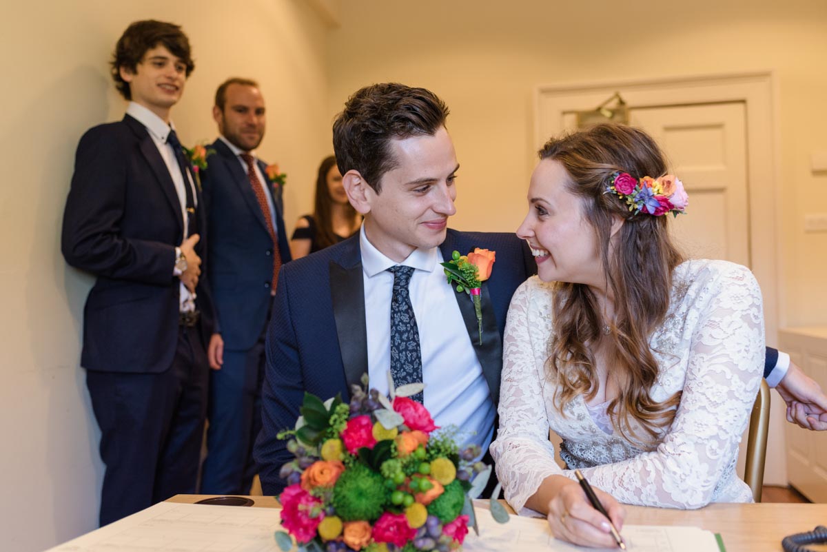 Photograph of Alex and James signing the register after their Danson House wedding ceremony