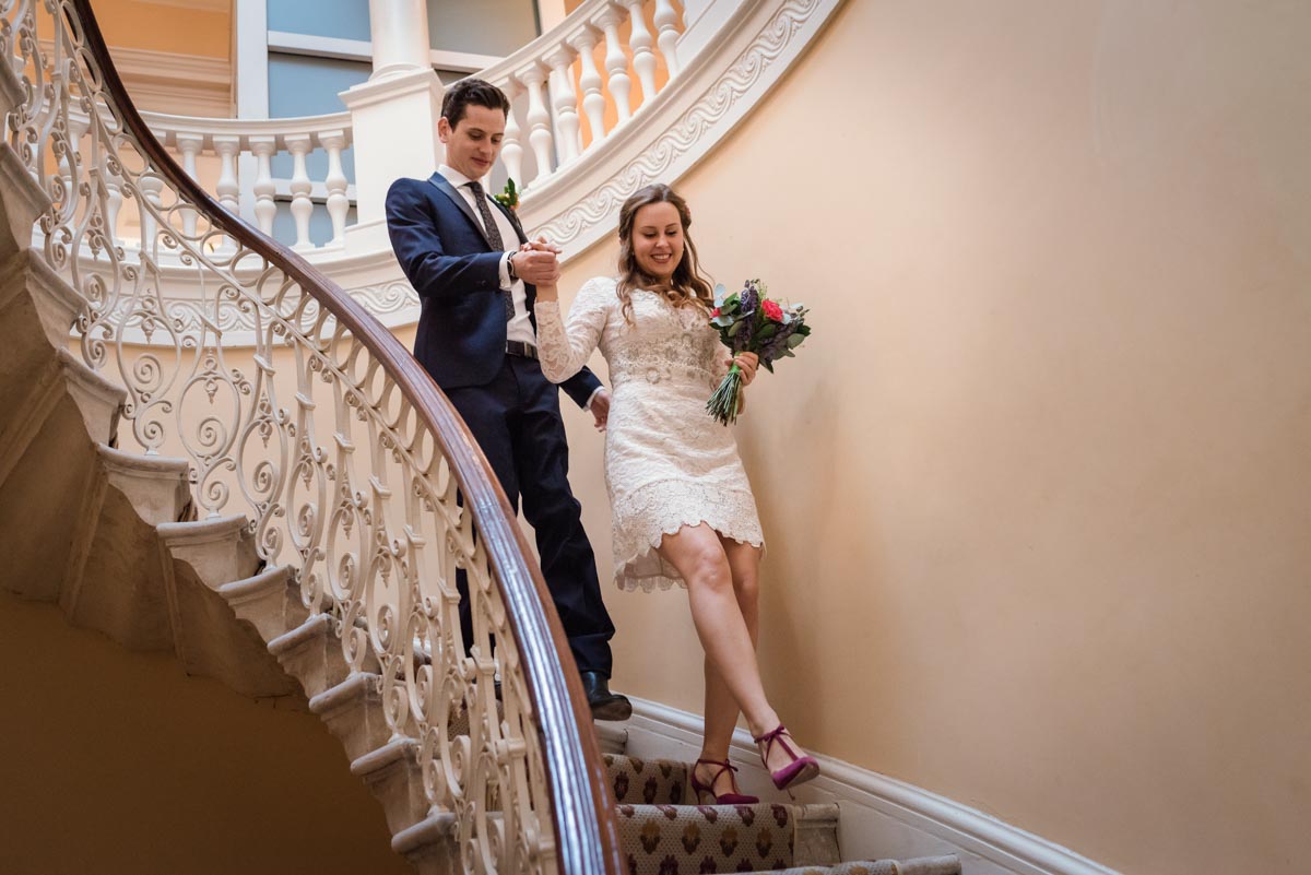 Alex and James decent the stairs at Danson House wedding venue