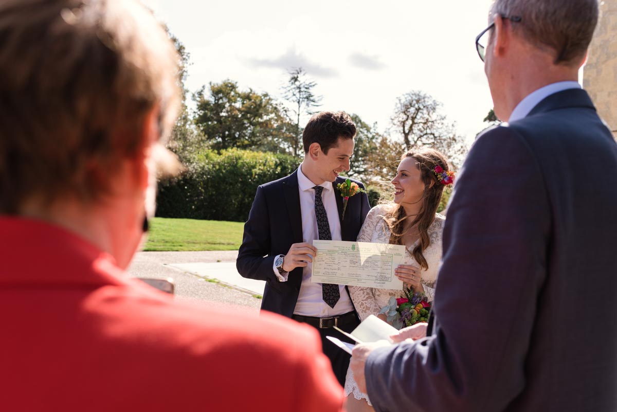 Photograph of james and Alex holding wedding certificate after their danson House wedding ceremony