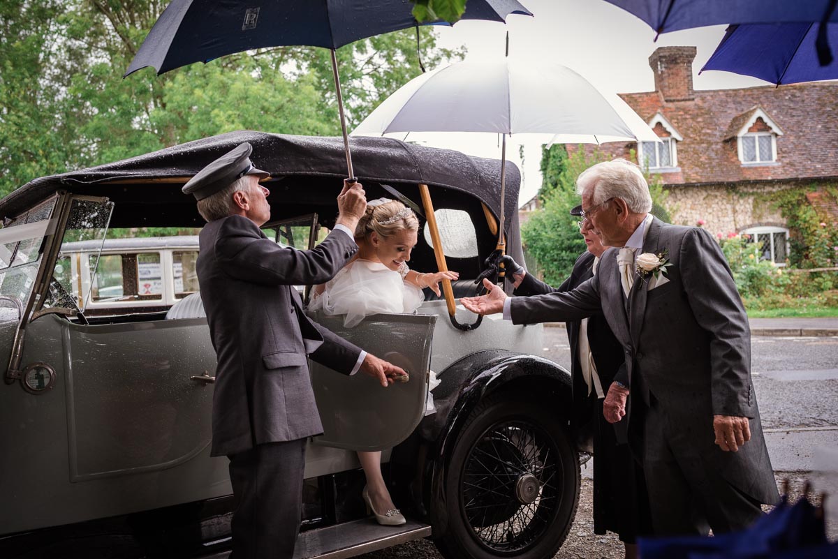 Rebecca is helped out of wedding car by her father