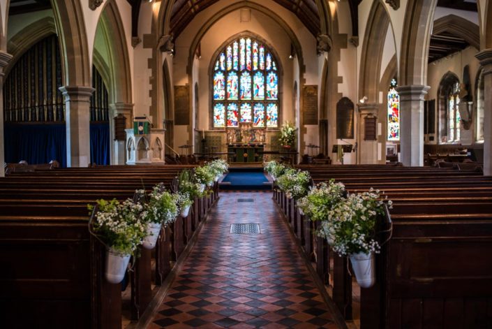 Flowers in ornate buckets decorate church pies for wedding