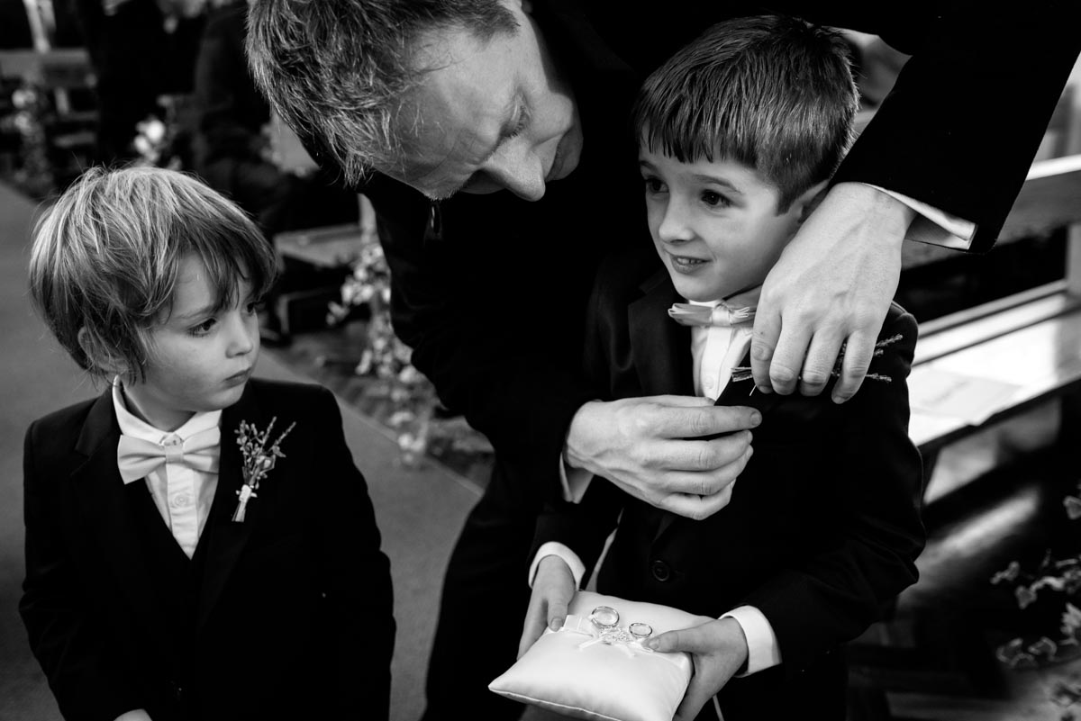 Page boys are photographed having their button holes fixed before wedding ceremony
