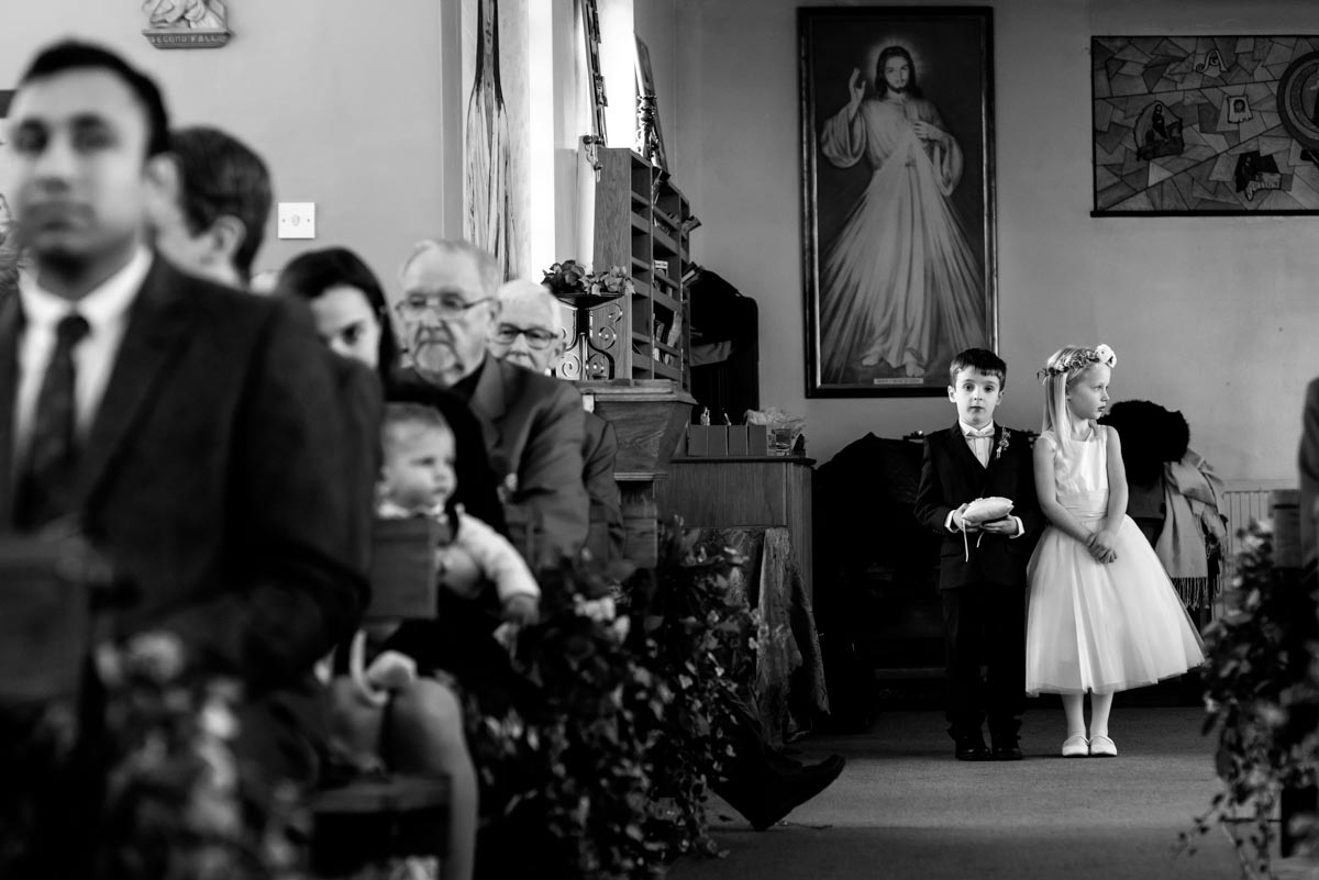 page boy and flower girl photographed waiting in church for brides arrival