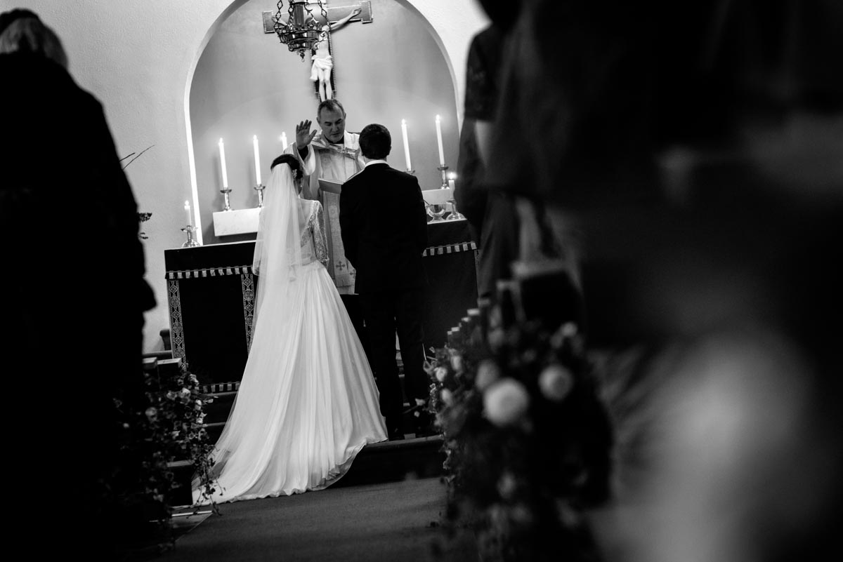 Photograph of Katherine and Tom being blessed by priest on their wedding day