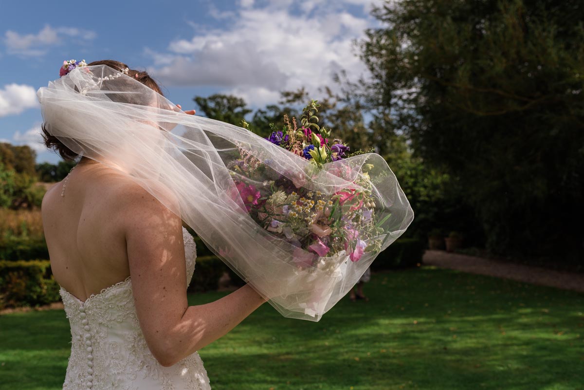 Photograph of veil covering wedding bouquet at secret garden wedding in Kent