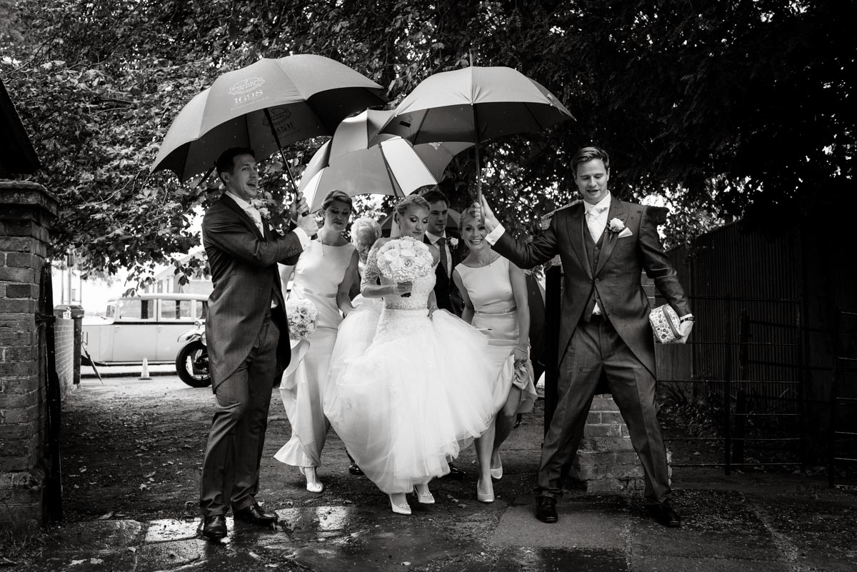 umbrellas shield bride from the rain before entering Kent church