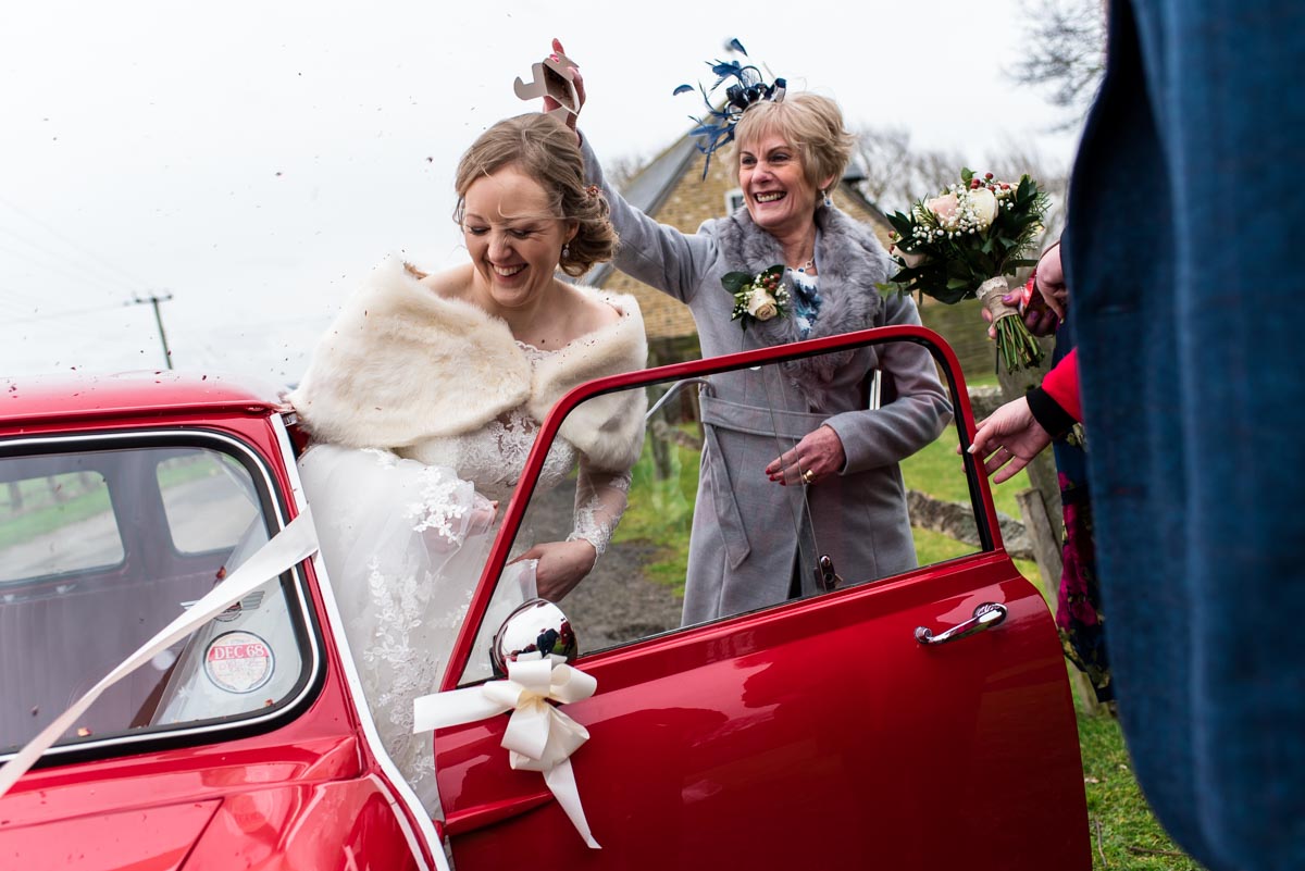 Rebecca is photographed having confetti thrown on her getting into wedding car