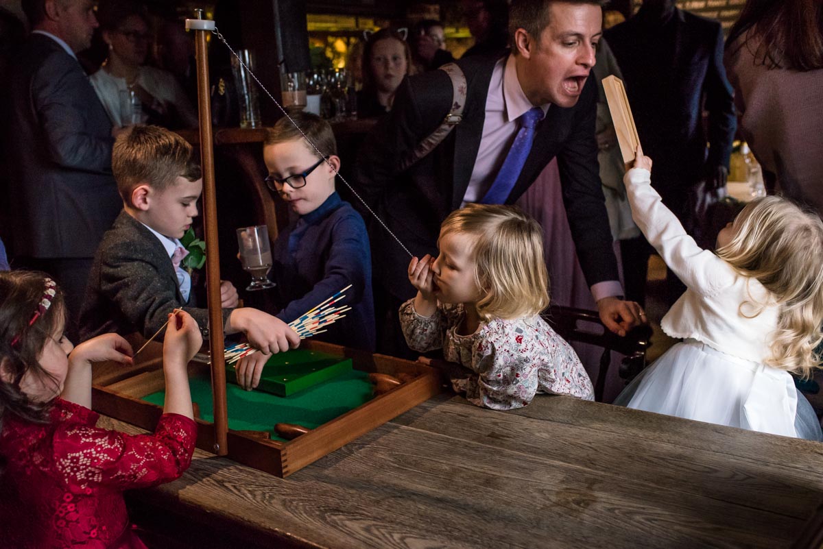 Wedding guests and children play indoor games at Stephen and Rebeccas Ferry House Inn wedding reception