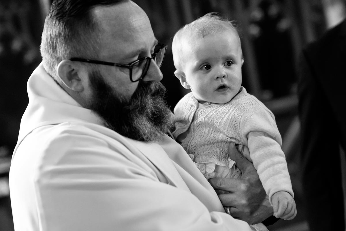 Kent christening photography. Vicar and Emily during baptism