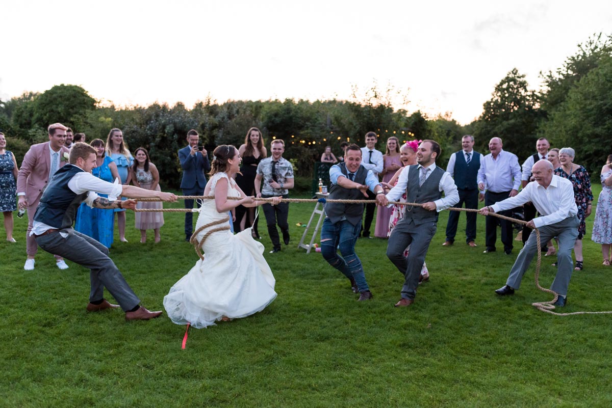 Bride and groom photographed playing tug of war at their Yalding Gardens wedding