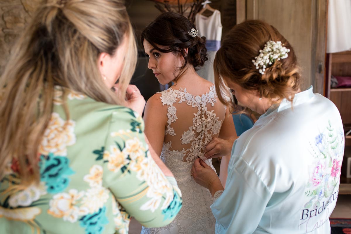 Photograph of Rebecca having the buttons on her wedding dress done up