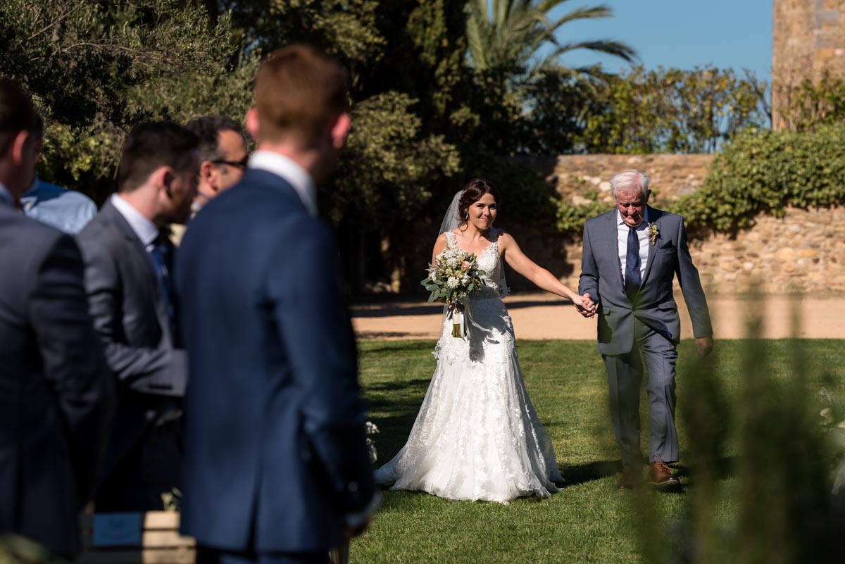 Rebecca is walked up the aisle on her wedding day at castell d'emporda