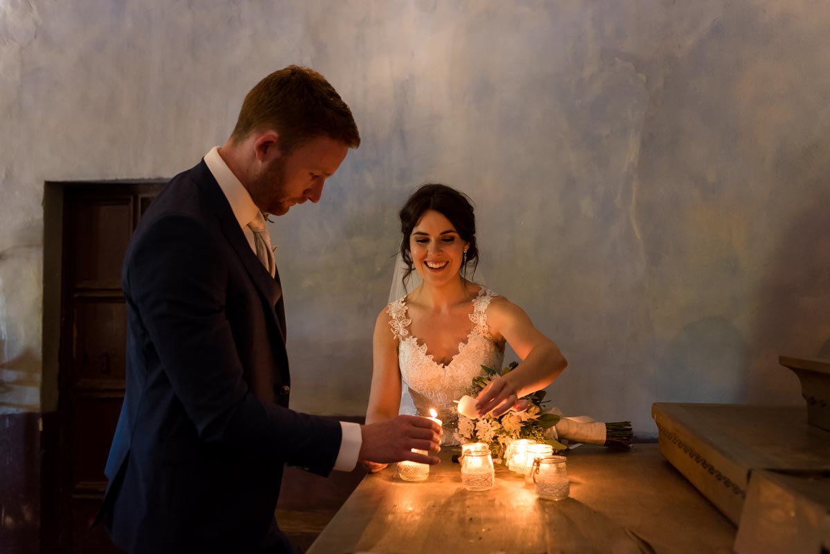 rebecca and matt light candles in chapel at castell d'emporda wedding venue