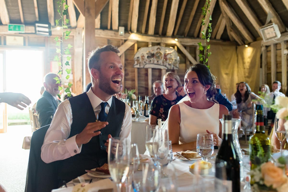 Sarah and Craig laughing during wedding speeches at odo's Barn in Kent