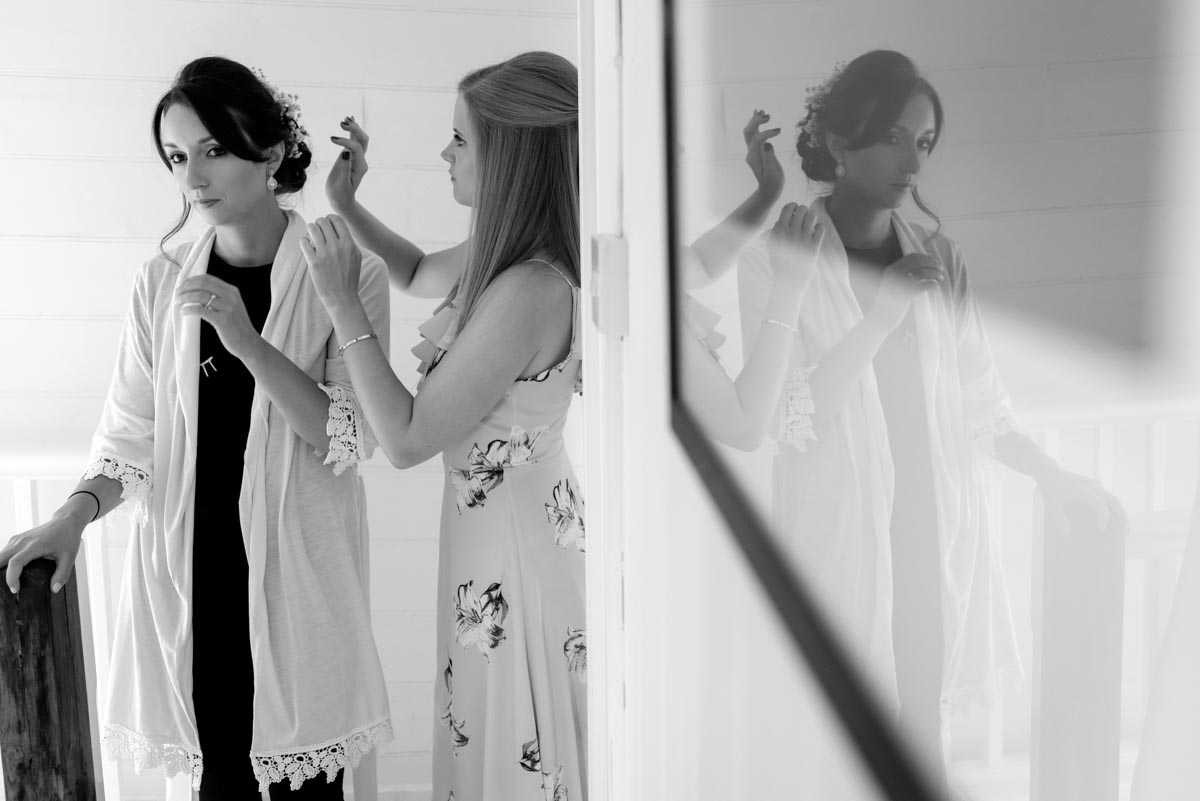 Bridesmaid makes finishing touches to sarahs hair before her wedding at Odo's Barn in Kent